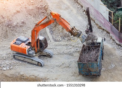 Loading metal reinforcement at a destroyed building with an excavator with a magnet