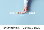 Loading new year 2022 to 2023 with hand putting wood cube in progress bar. Start new year 2023 with goal plan, goal concept, strategy.