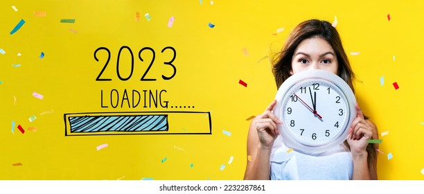 Loading new year 2023 with young woman holding a clock showing nearly 12 - Shutterstock ID 2232287861