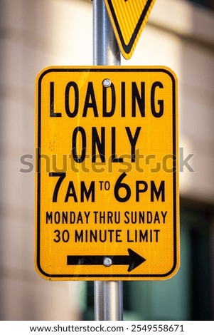 Loading Only 7am - 6 pm Monday thrugh Sunday 30 minute limit yellow rectangular street sign on the side of a road, blurred office building in the background