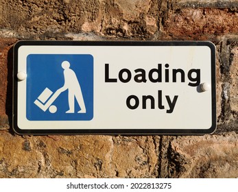 A loading only sign on a cobbled stone wall 