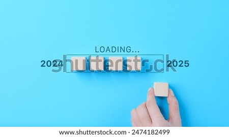 Loading Progress Bar from 2024 to 2025 with Wooden Blocks. A hand places wooden blocks in a row, creating a progress bar transitioning from 2024 to 2025, symbolizing the new year and future progress.