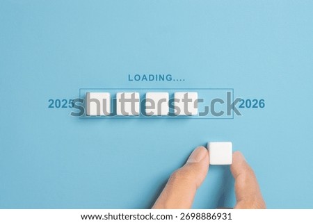 Loading Progress Bar from 2025 to 2026 with dice. A hand places wooden blocks in a row, creating a progress bar transitioning from 2025 to 2026, symbolizing the new year and future progress