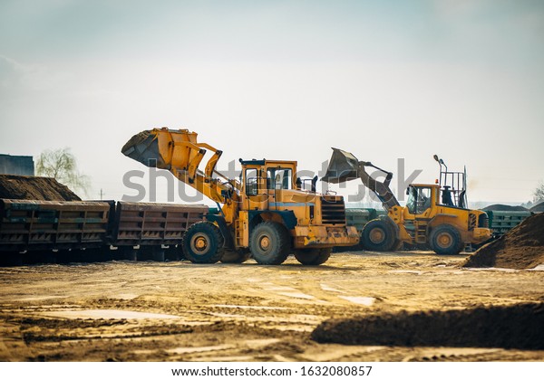 Loading railway wagons\
with stone, a tractor loads wagons with stone, transporting rubble\
on a railway