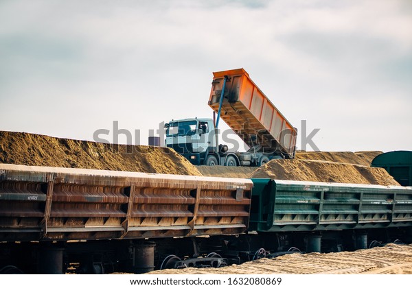 Loading railway wagons\
with stone, a tractor loads wagons with stone, transporting rubble\
on a railway