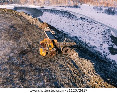 Loading rock mass into a truck. Excavator at work. Mining. flying drone. view from above. mine coal. miner's day. winter snow.