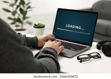Loading screen displaying progress. Man working on laptop at table indoors, closeup - Powered by Shutterstock - Get 15% off with code: PIKWIZARD15
