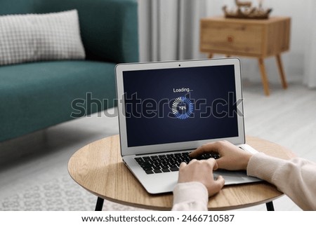 Loading screen displaying progress. Woman working on laptop at table indoors, closeup