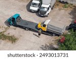 Loading a small inoperable truck onto a tow truck in a parking lot.