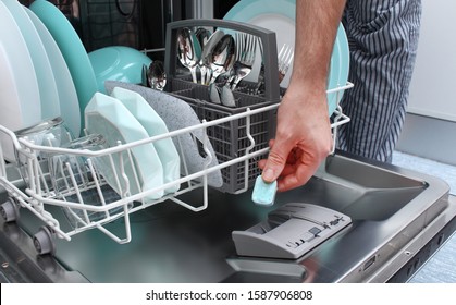 Loading the tablet into the dishwasher. A man puts the tablet in the dishwasher to wash dirty dishes. - Powered by Shutterstock