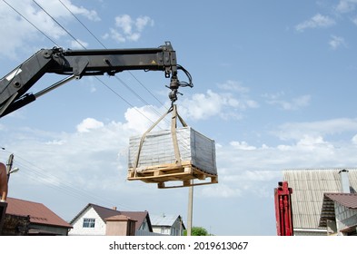 Loading Tiles To The Ground From A Car. Delivery And Unloading Of Building Materials To The House. Truck Crane Unloaded Street Tiles.