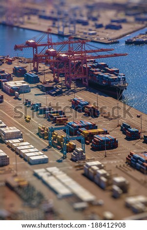 Loading a transport ship with cargo, containers, with tilt-shift lens effect from bird's eye perspective