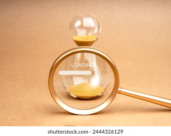 Loading update concept. Text "Loading..." on golden hourglass in magnifying glass lens on brown recycle paper background, minimal style. Setting a time limit, mini-deadline to work. - Powered by Shutterstock