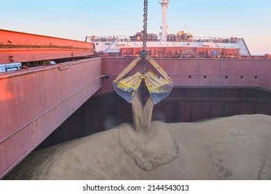 Loading of wheat, barley in bulk using steel grab into cargo hold of bulk carrier, cargo ship