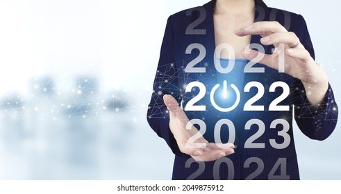 Loading year 2021 to 2022. Start concept. Two hand holding virtual holographic 2022 icon with light blurred background. Welcome year 2022. Business new year card concept.