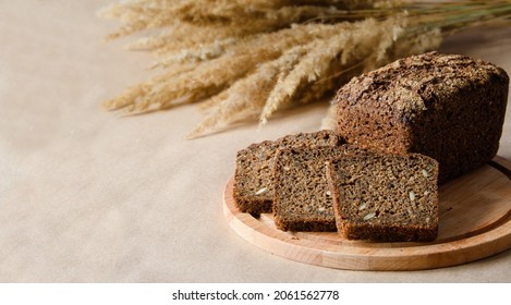A loaf of fresh rye bread and three slices on a board. Left empty empty space