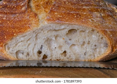 Loaf Of Home Made Craft Bread On Wooden Plate With Sliced Heel And Metal Knife.