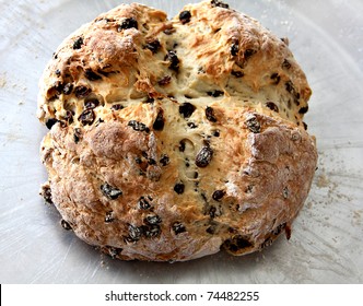 A loaf of Irish Soda Bread with raisins on baking sheet.