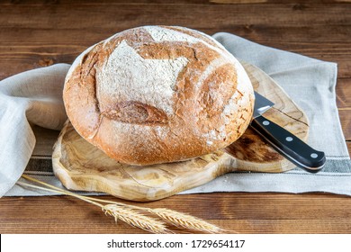 Loaf of round integral bread and knife on the wooden cutting board of the kitchen. Healthy diet integral bread.  - Shutterstock ID 1729654117