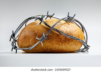 A loaf of round wheat bread wrapped with barbed wire. The concept of food crisis, food shortage.