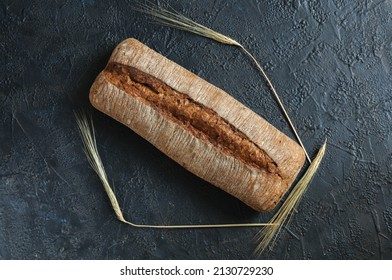 A Loaf Of Rustic Rye Bread On A Black Background With Ears Of Rye. View From Above