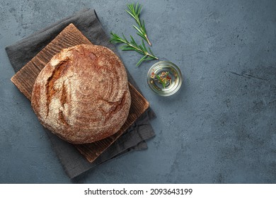 A loaf of rye bread with rosemary and olive oil on a gray-blue background. Top view, copy space. - Powered by Shutterstock