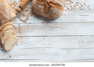 Loafs of bread and rolling pin on rustic table with grain