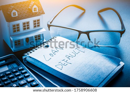 loan default word on note with us dollars and stuff on  desk.