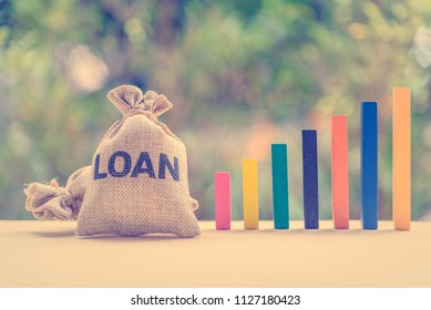 Loan or lending cash to buy asset concept : Loan bag and color wood bar graphs in different height on a table, depicts a borrower always borrow money from lender in higher amount and never payback