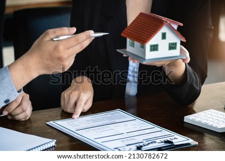 Loan signing concept, refinancing, home and land purchase, rental accommodation, female real estate agent or bank employee pointing to a contract or agreement with a male client to  to Buy a dwelling