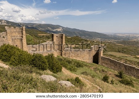 Loarre, Spain. High angle view from inside the eleventh century Romanesque Castle of Loarre showing its defensive stone walls, rounded towers and a vast landscape background under a blue sky