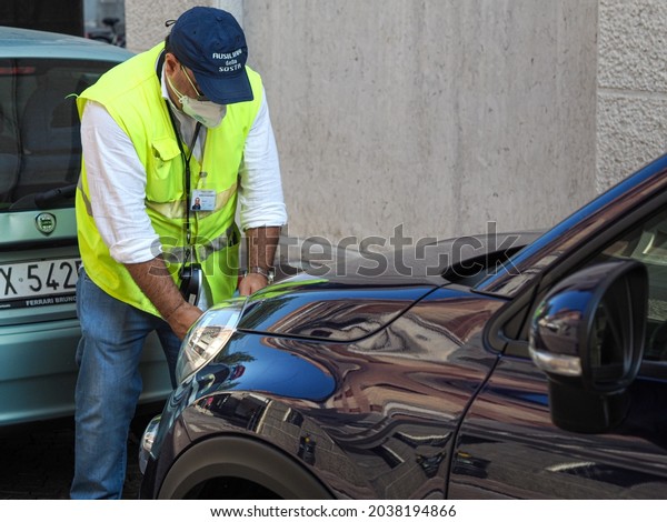 LOBARDY, ITALY - Aug\
19, 2021: A traffic assistant issuing a parking fine for a\
violation with a mobile\
app