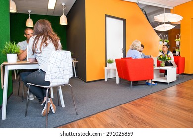 Lobby And Multi-purpose Waiting Area, With Several Groups Of People Sitting At Tables During Informal Meetings Of A Modern Styled Office