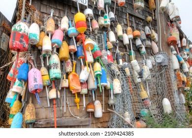 lobster buoys of various color on shack on ocean side