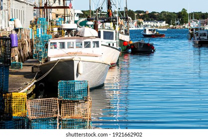 Lobster fishing boats docked behind stores in a canal in Porland Maine with lobster traps and fishing tools stacked on the dock. - Shutterstock ID 1921662902