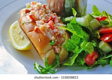 A Lobster Roll Sandwich With A Green Salad And French Fries