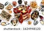 Lobster and seafood party table with oyster, crab, clams, shrimps and crayfish on white tablecloth photographed from above