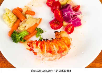 Lobster Tail Dinner With Steamed Vegetables And Pickled Tomatoes And Purple Onions On White Plate