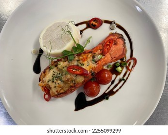 Lobster Thermidor is a French dish of lobster meat cooked in a rich wine sauce, stuffed back into a lobster shell, and browned. The sauce is often a mixture of egg yolks and brandy - Shutterstock ID 2255099299