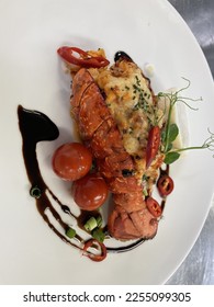 Lobster Thermidor is a French dish of lobster meat cooked in a rich wine sauce, stuffed back into a lobster shell, and browned. The sauce is often a mixture of egg yolks and brandy - Shutterstock ID 2255099305