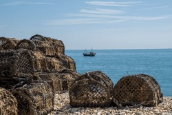Lobster Traps On The Beach With A Fishing Boat In The Sea In The Background In Selsey West Sussex England