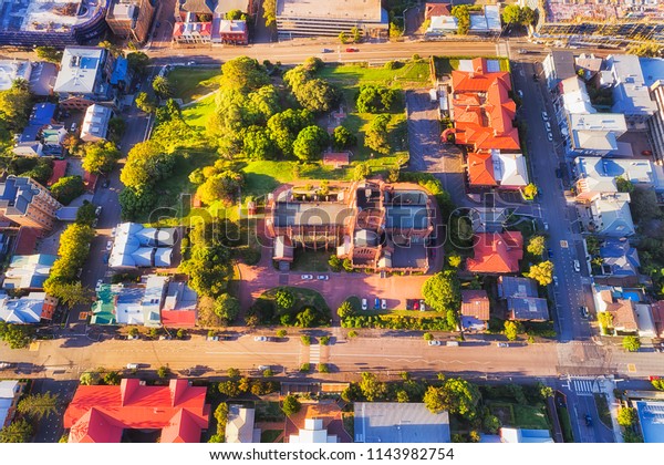 Local architectural historic landmark in modern\
city Newcastle of Australia. Aerial overhead view down to Cathedral\
site, roof and local park surrounded by residential houses and\
streets.