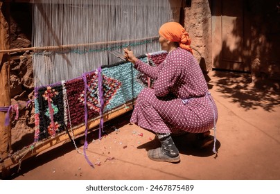 Local Berber woman hand weaving a rug in traditional village, Ourika Valley, Morocco. Authentic handmade artisan craft, cultural travel - Powered by Shutterstock