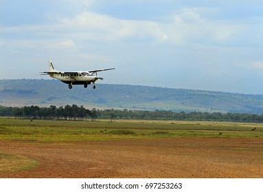 A Local Biplane Landing On A Dirt Strip In The African Bush.  Flying Into The Bush Is Popular Because Of The Long Distances And Bumpy Roads.  Masai Mara, Kenya 2011