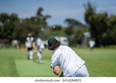 a local cricket match being played on a green cricket oval in summer in australia. australian cricketer batting and bowling in a game in summer - Powered by Shutterstock