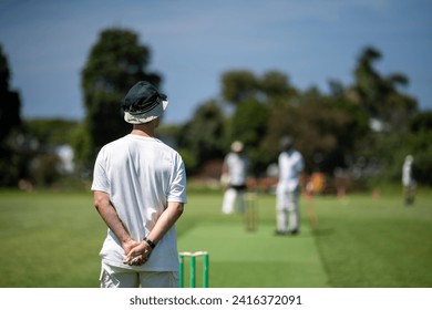 a local cricket match being played on a green cricket oval in summer in australia. australian cricketer batting and bowling in a game in summer - Powered by Shutterstock