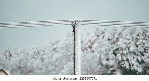Local electric pole covered with ice and snow. Concept of electricty and blackouts problem during winter snowstroms in rural areas. - Shutterstock ID 2251807891