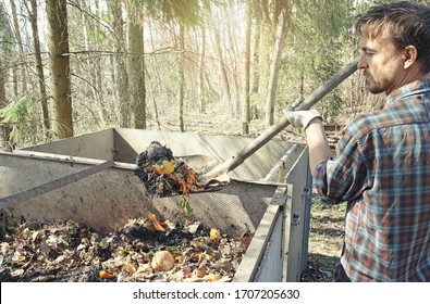 Local farmer holding shovel full of compostable food scraps over compost heap. Composting, permaculture, zero waste gardening, sustainable living. Kitchen and garden waste leftovers to fertilizer.