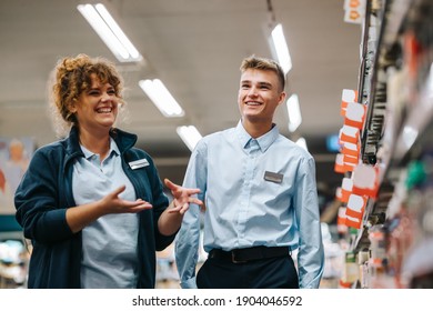 Local Grocery Store Manager Training New Male Employee. Woman Explaining Inventory System Supermarket To Young Worker.