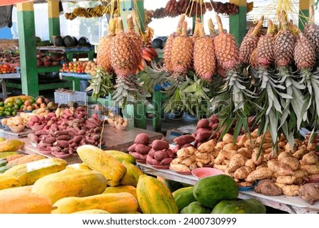 Local market stall with fresh, colorful tropical fruit and vegetables including pineapples, papaya and sweet potatoes in Dili, Timor-Leste, Southeast Asia